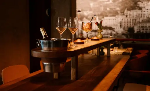 Twee glazen rosé, een cocktail en een fles in een ijsemmer op de bar bij Alberto's