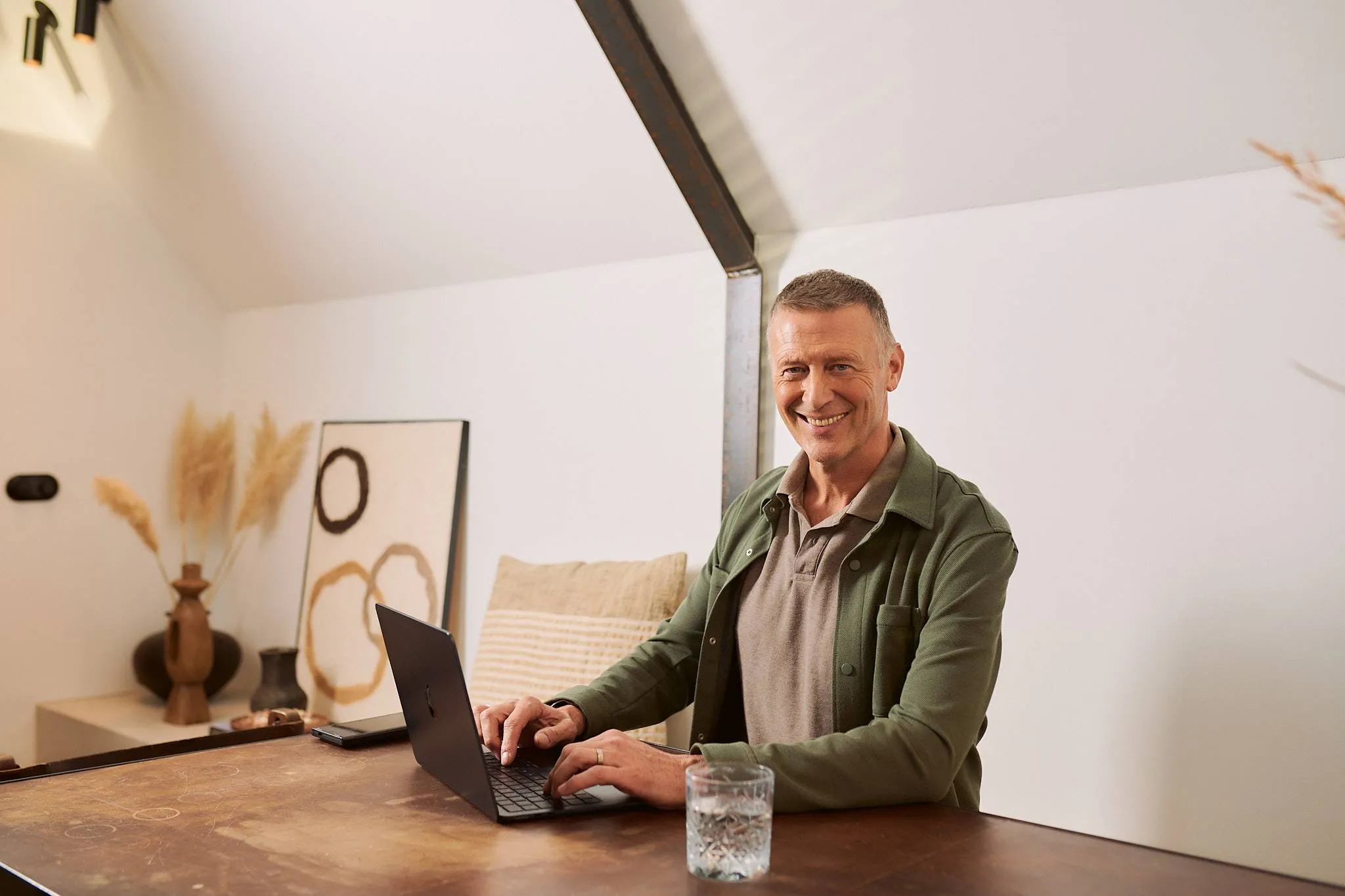 een man achter een laptop kijkend naar de camera met een fhm logo