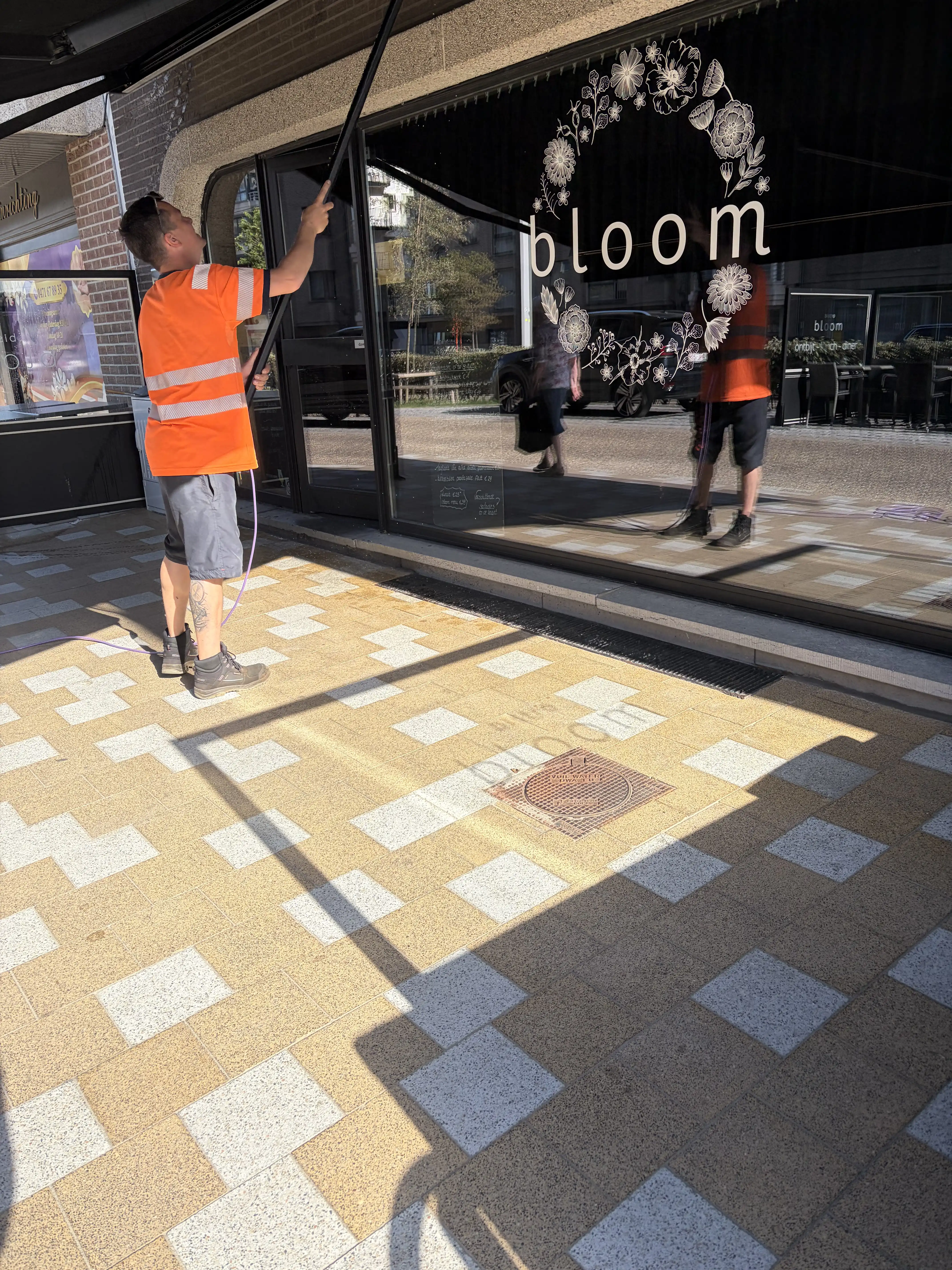 Kenneth wast het raam tijdens de reiniging van het terras van Restaurant Bloom