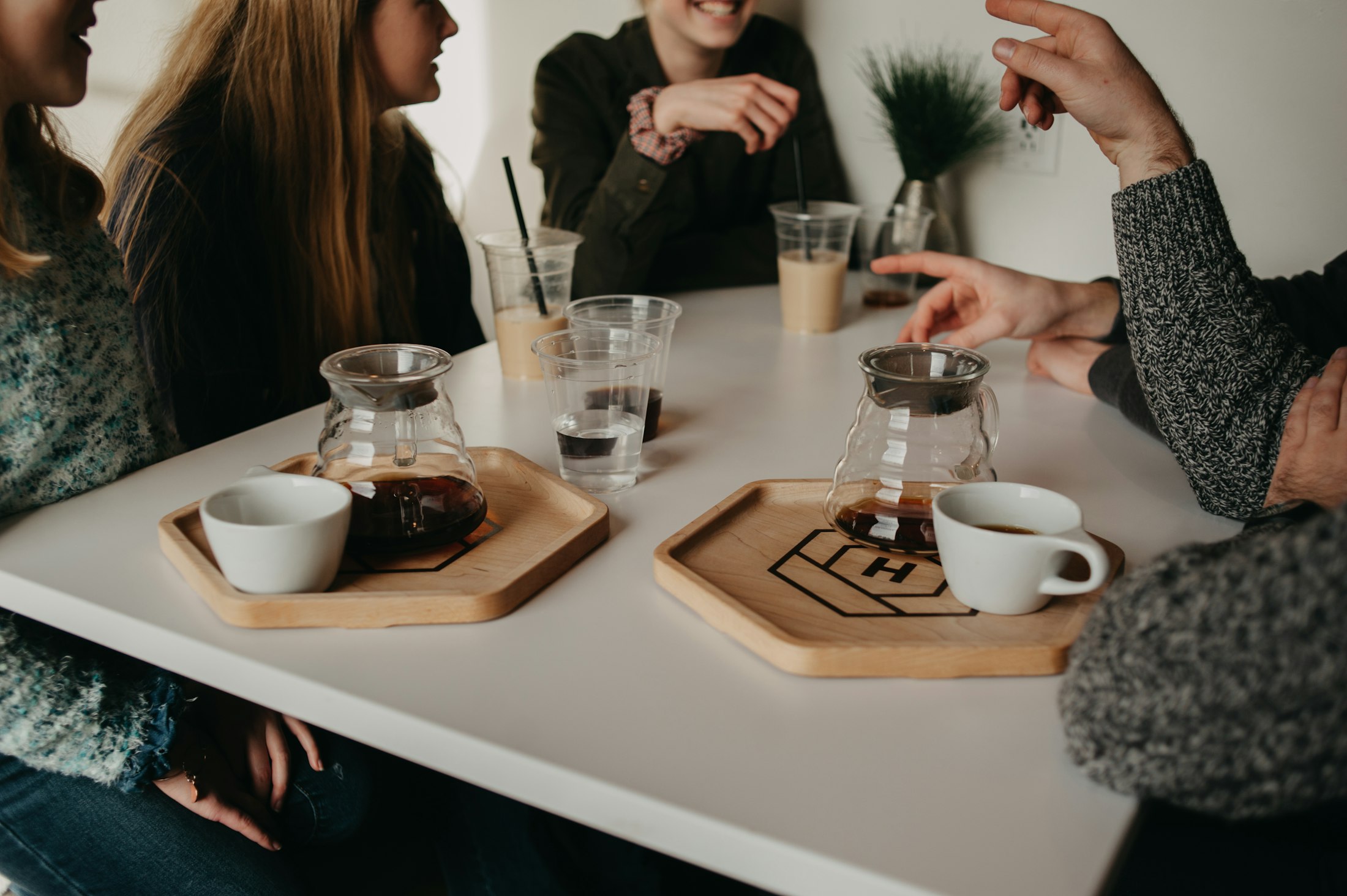 Friends around a table sharing pour-over coffee on wooden trays