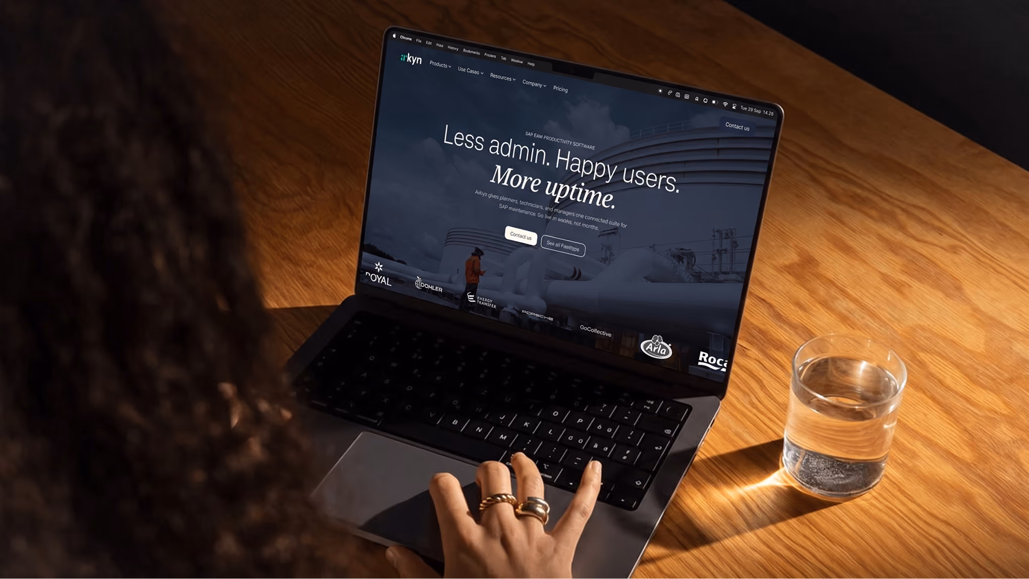 Arkyn homepage on a laptop, with the headline “Less admin. Happy users. More uptime.” above an industrial scene.