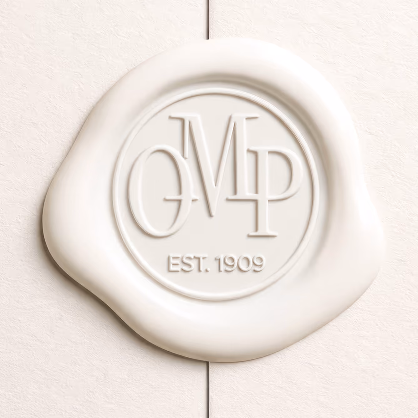 The circular OMP monogram embossed into a cream seal, with “Est. 1909” beneath the initials.