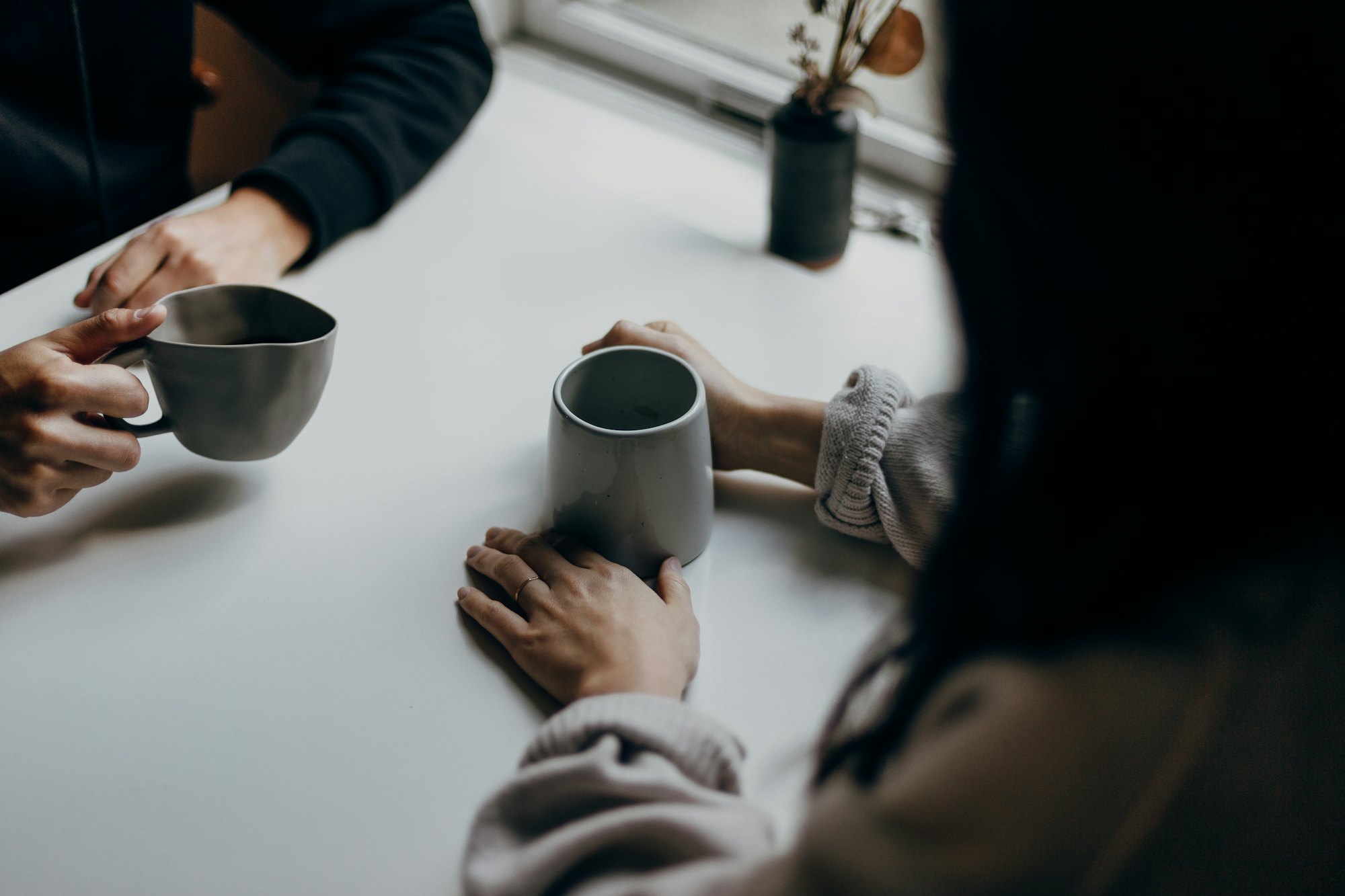 Deux personnes échangent autour d'une tasse de café, dans un moment d'écoute.