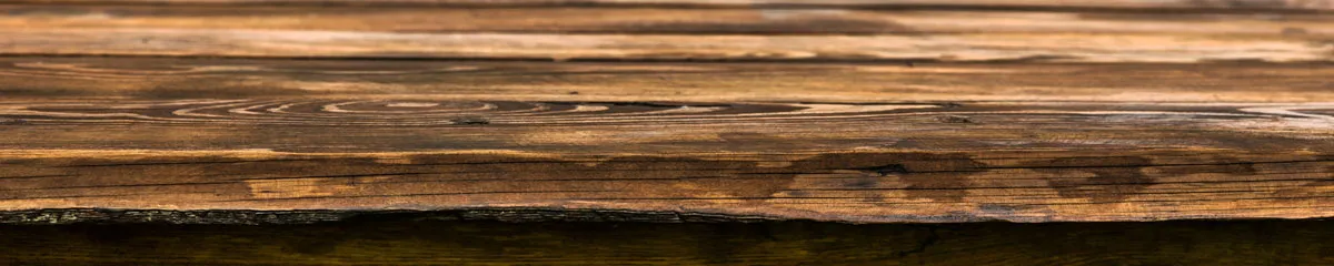 Nahaufnahme eines wettergegerbten Holzbretts mit sichtbarer Maserung.