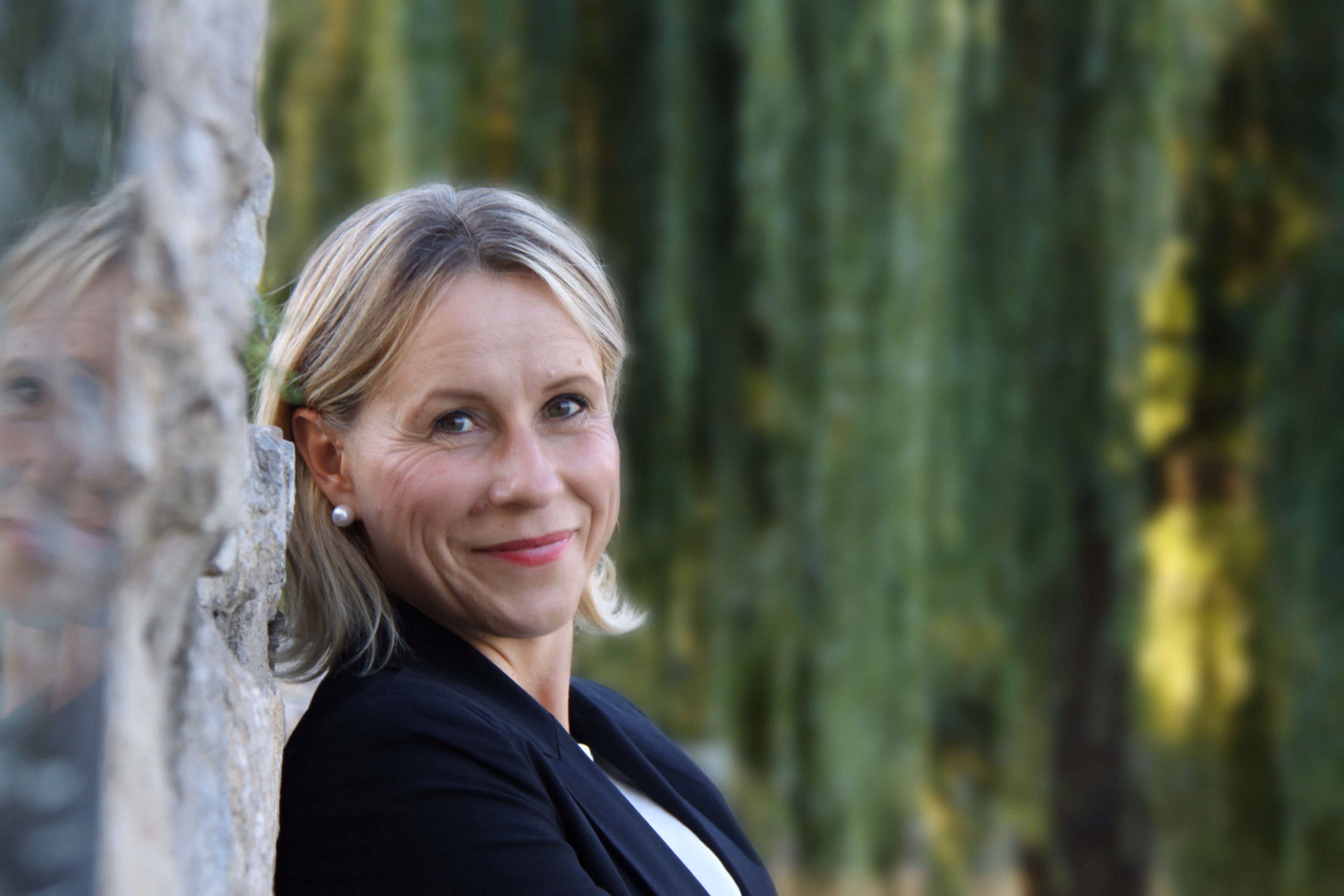 Anke Ruprecht, lächelnd an eine Steinfläche gelehnt – persönliche Begleiterin für besondere Erlebnisse als Perlentaucherin.