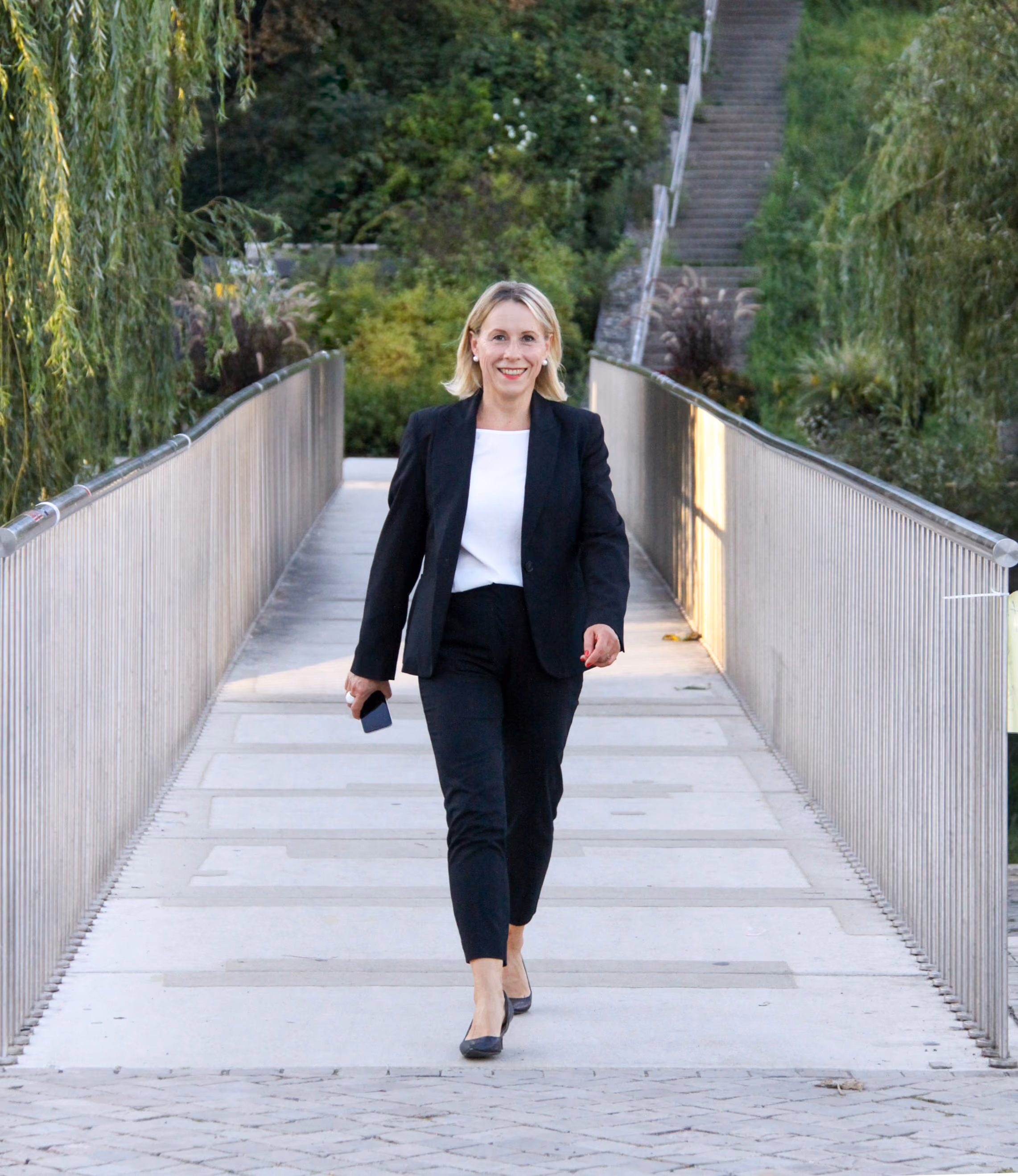 Anke Ruprecht als Perlentaucherin unterwegs auf einer Fußgängerbrücke im Grünen.