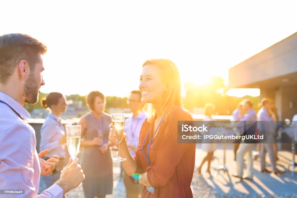 Menschen bei einem geselligen Outdoor-Event mit Champagner in der Hand und Gesprächen bei sonnigem Wetter.