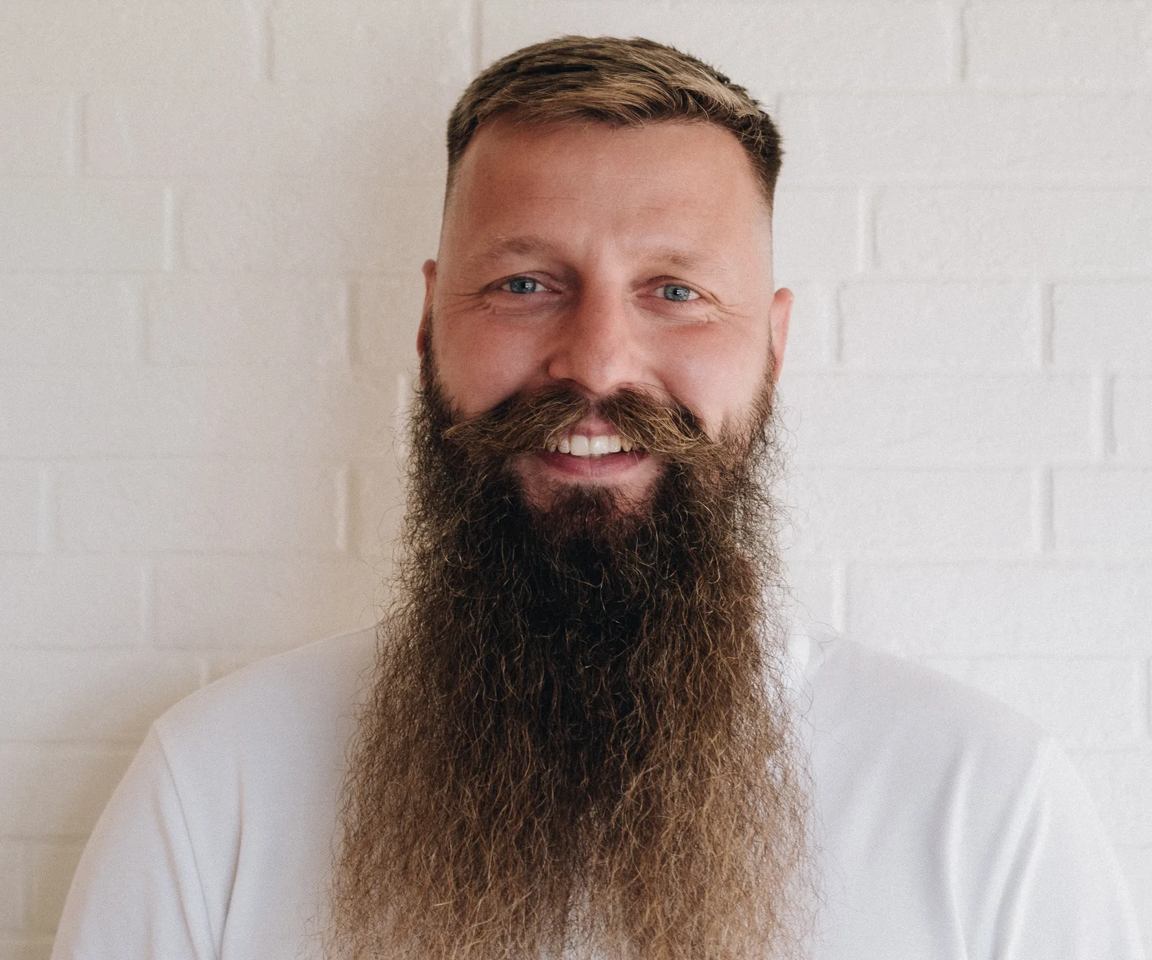 Piotr, Head of Technology at Bnewable, smiling in a white t-shirt in front of a white brick wall