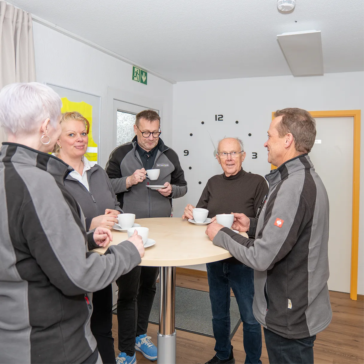Mitarbeitende im Gespräch an einem Stehtisch