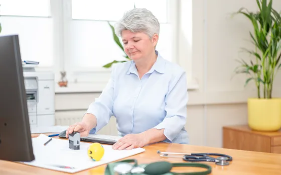 Arbeitsmedizinische Untersuchung am Schreibtisch mit Messgerät und Stethoskop