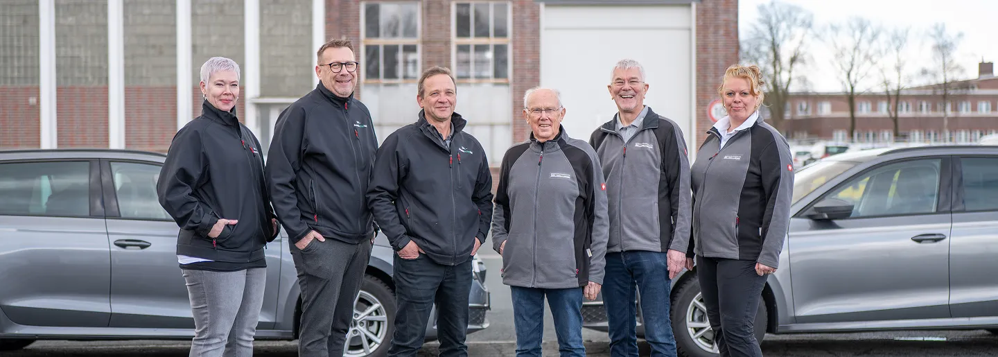 Team vor den Firmenfahrzeugen am Betriebsgelände