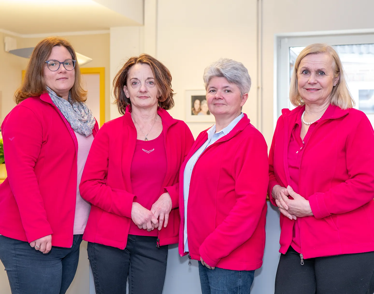 Vier Mitarbeiterinnen in roter Firmenkleidung