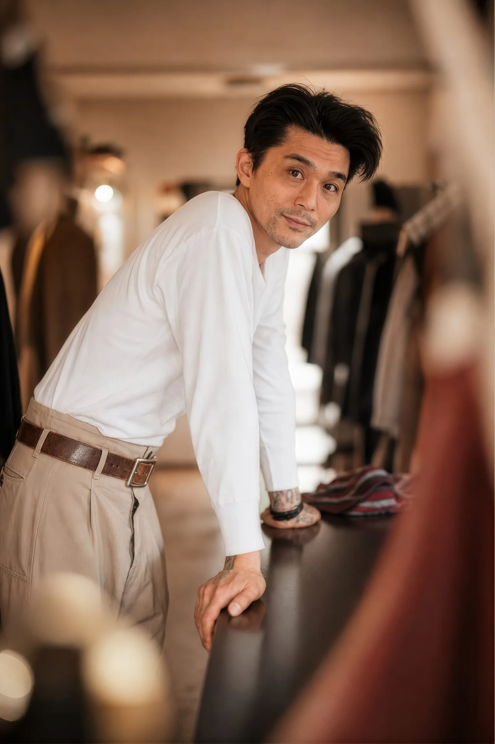 A shop owner leaning on the counter of his clothing store