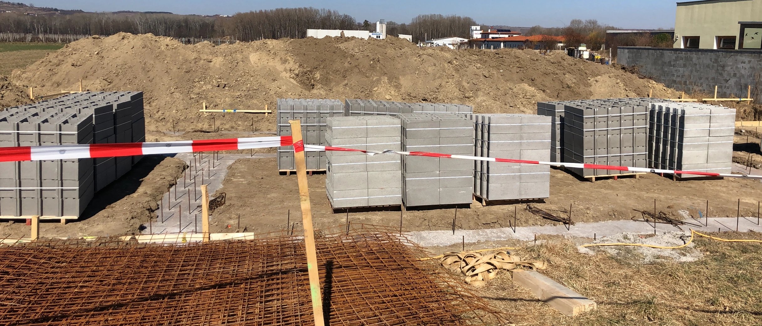 Paletten mit Schalungssteinen auf einer Baustelle, davor Baustahlmatten