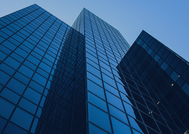 Looking up at three modern glass skyscrapers with reflective blue windows against a clear blue sky.