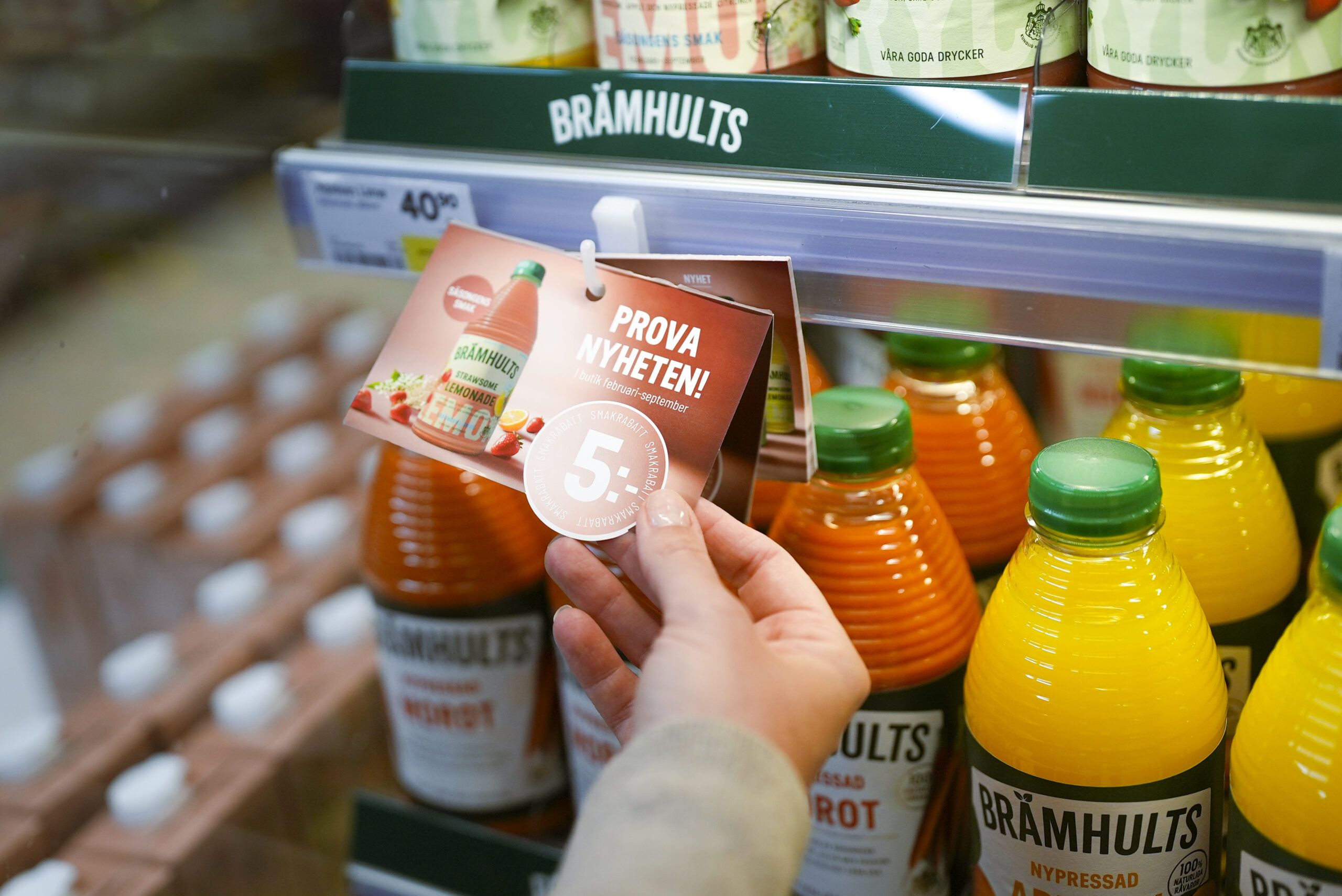 Hand som tar en flaska juice ur kylhyllan