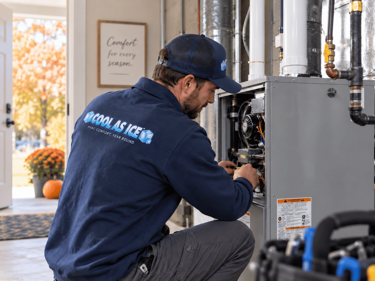 Technician in blue shirt checking an outdoor HVAC unit with pressure gauges and a tool bag nearby.