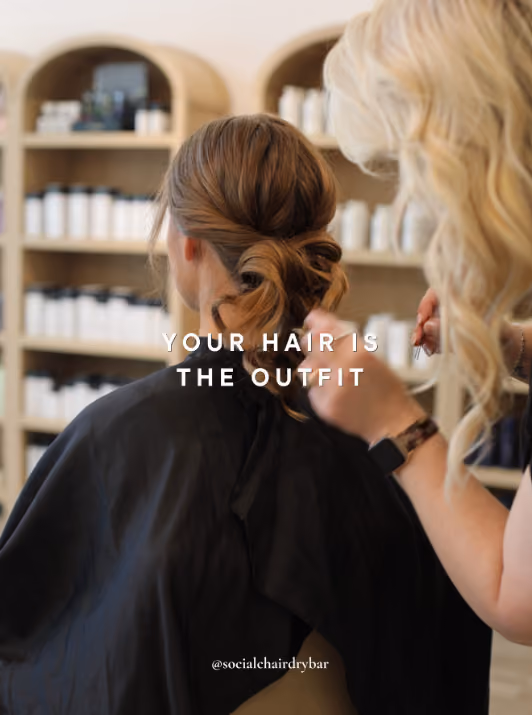 Stylist finishing a low twisted bun on a client at the styling chair