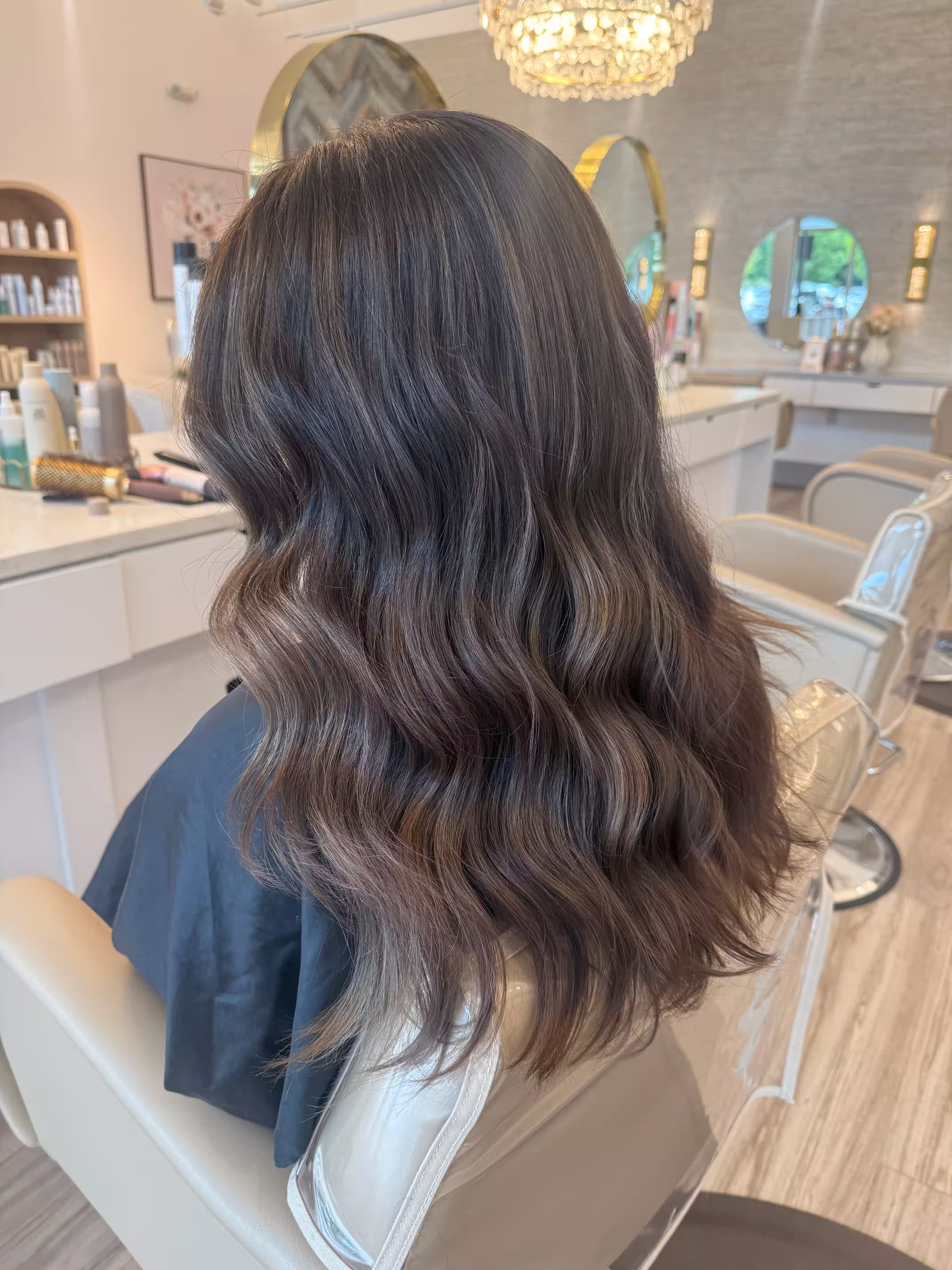 Client with long dark waves seen from behind in the salon