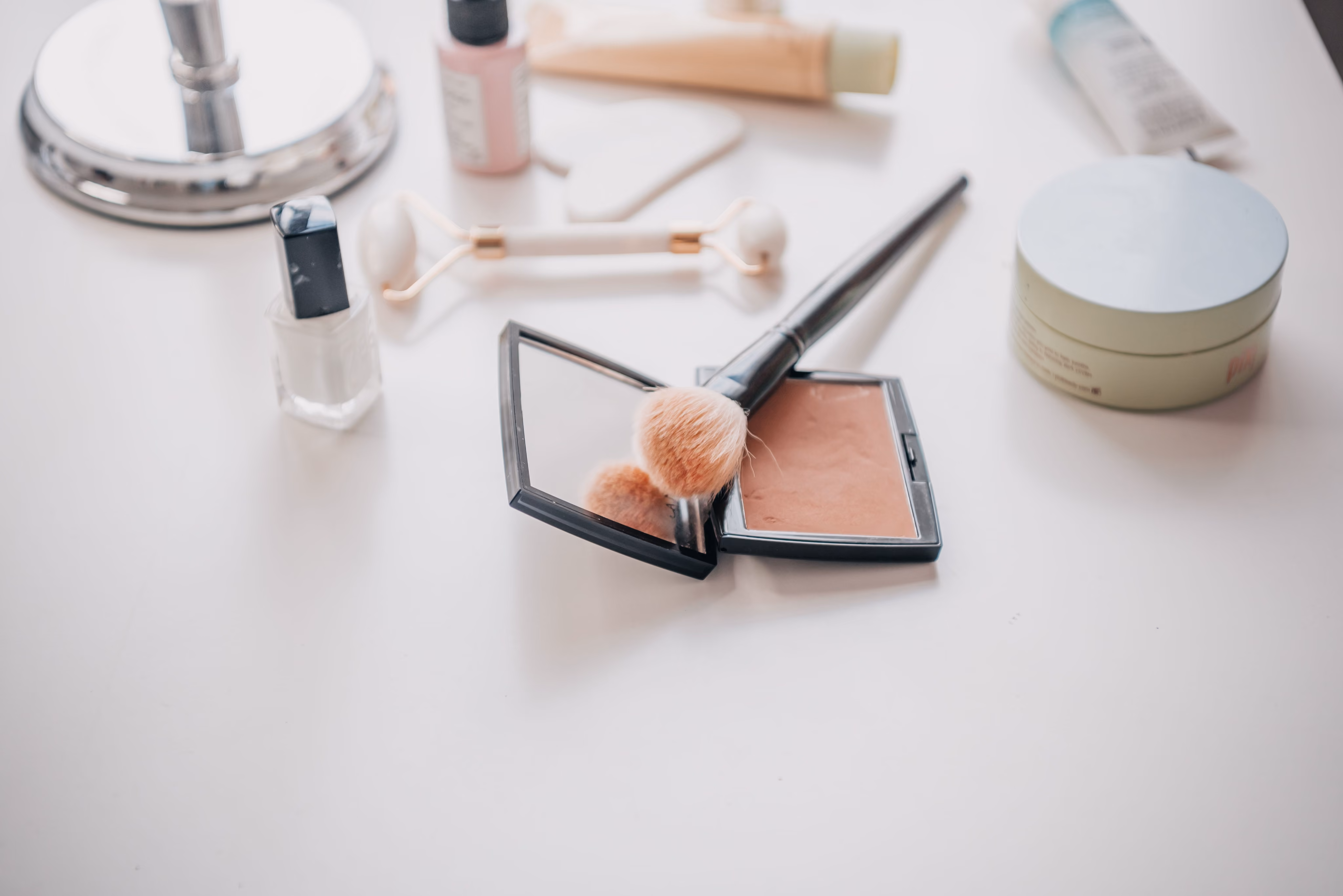 Makeup and beauty products arranged on a dressing table, including a blush compact and brushes