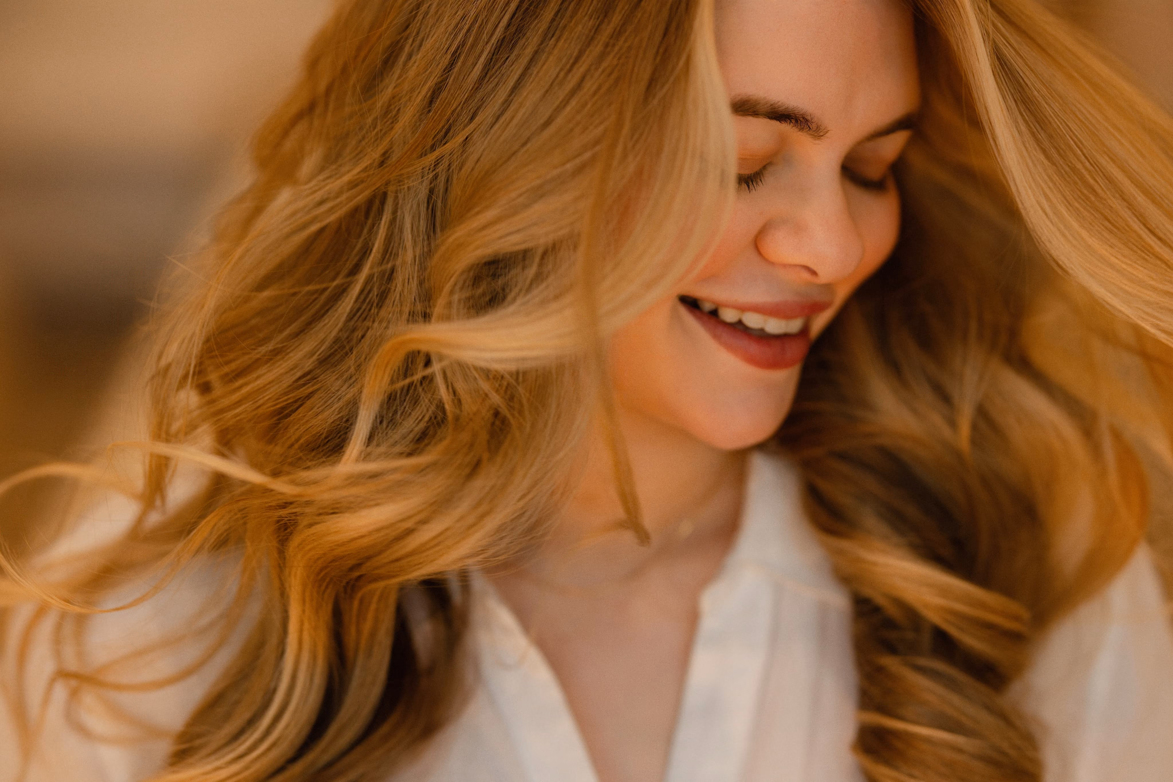 Smiling client with long, loosely waved blonde hair styled at The Social Chair