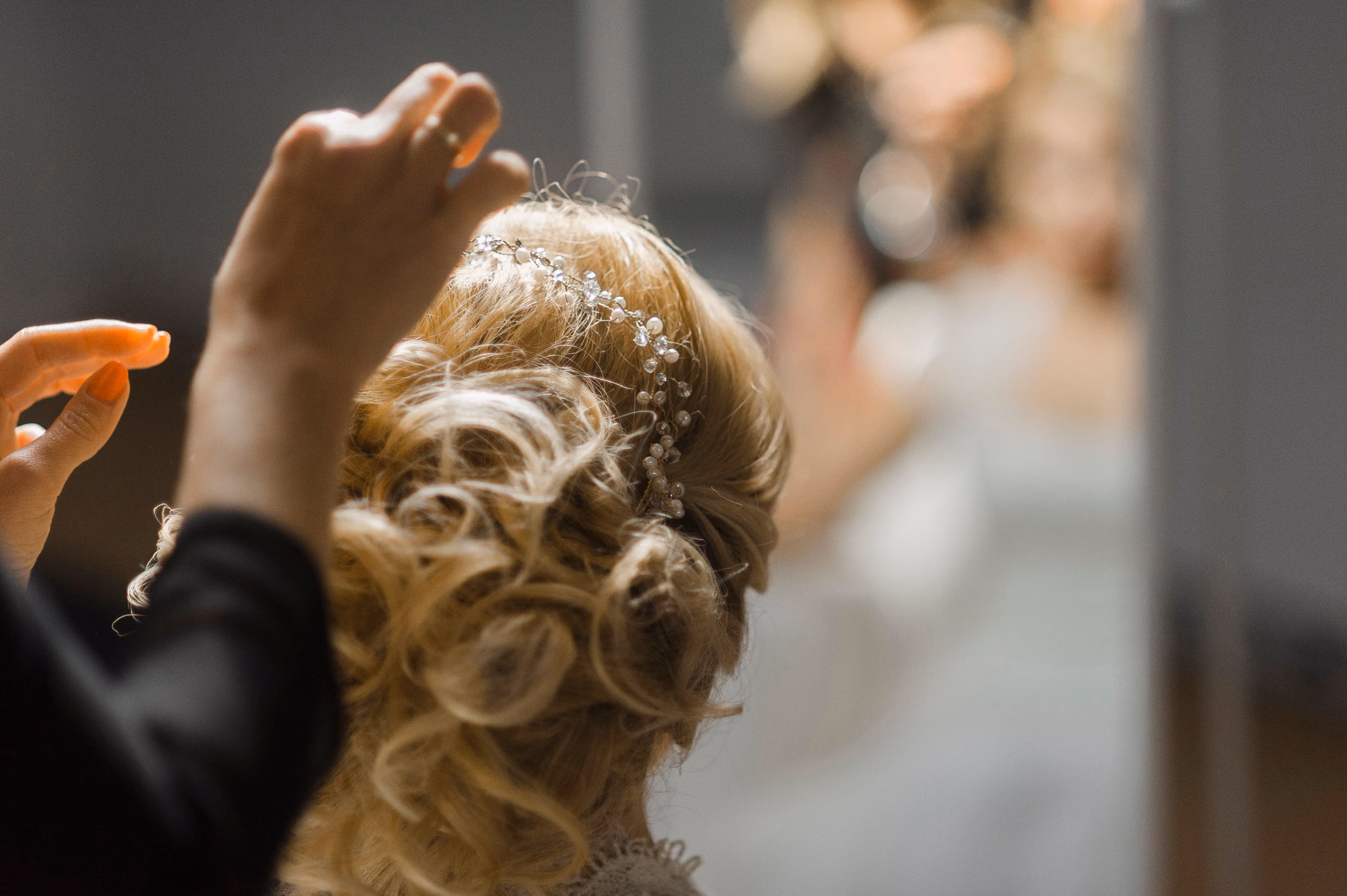 Stylist pinning a soft blonde curled updo