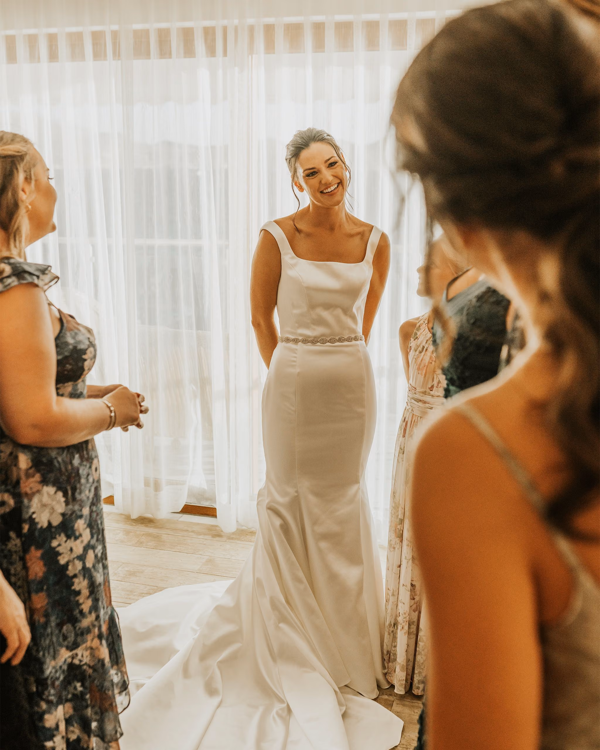 Bride in her gown with bridesmaids in a bright getting-ready room