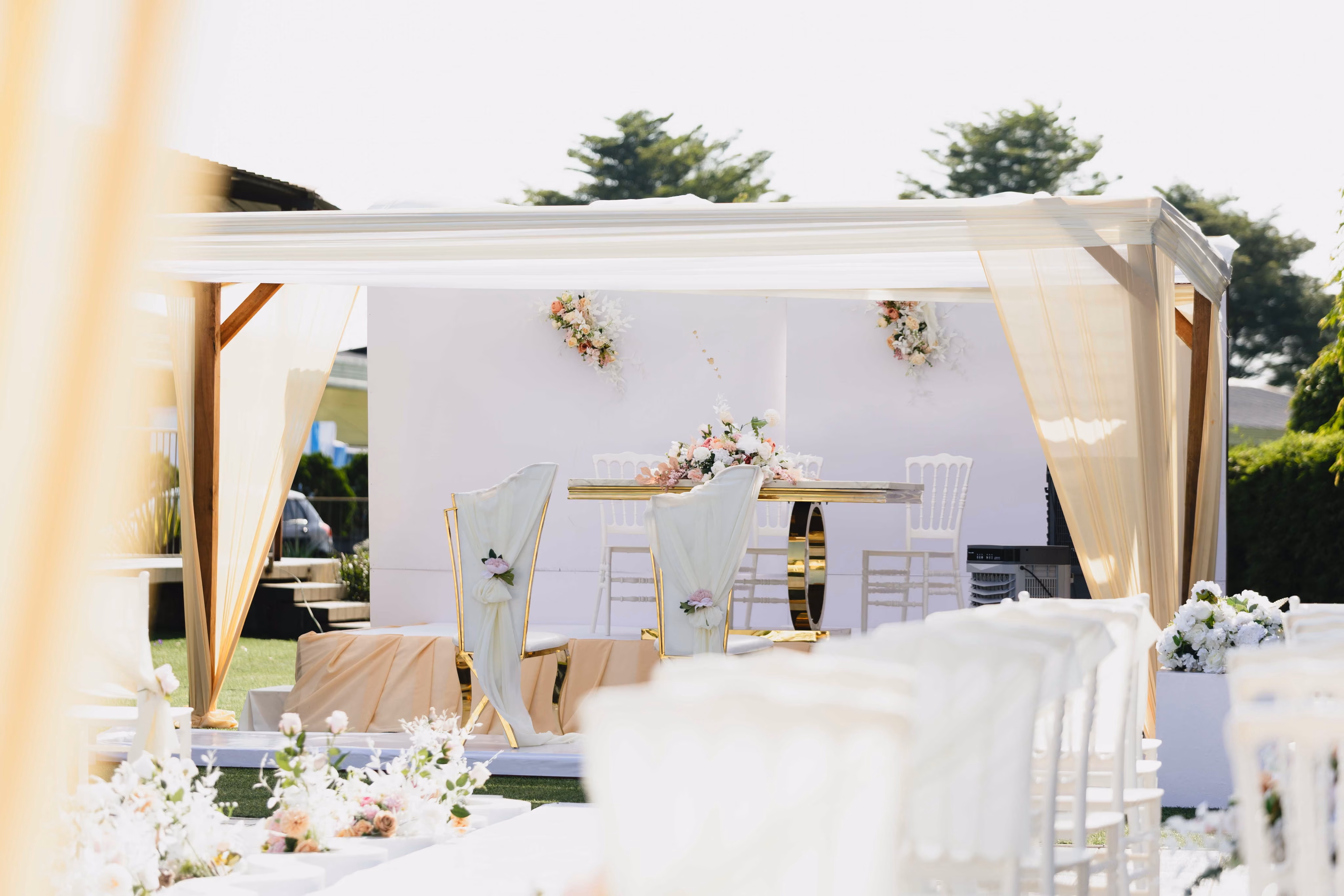 Outdoor wedding ceremony set up with white florals and draped seating