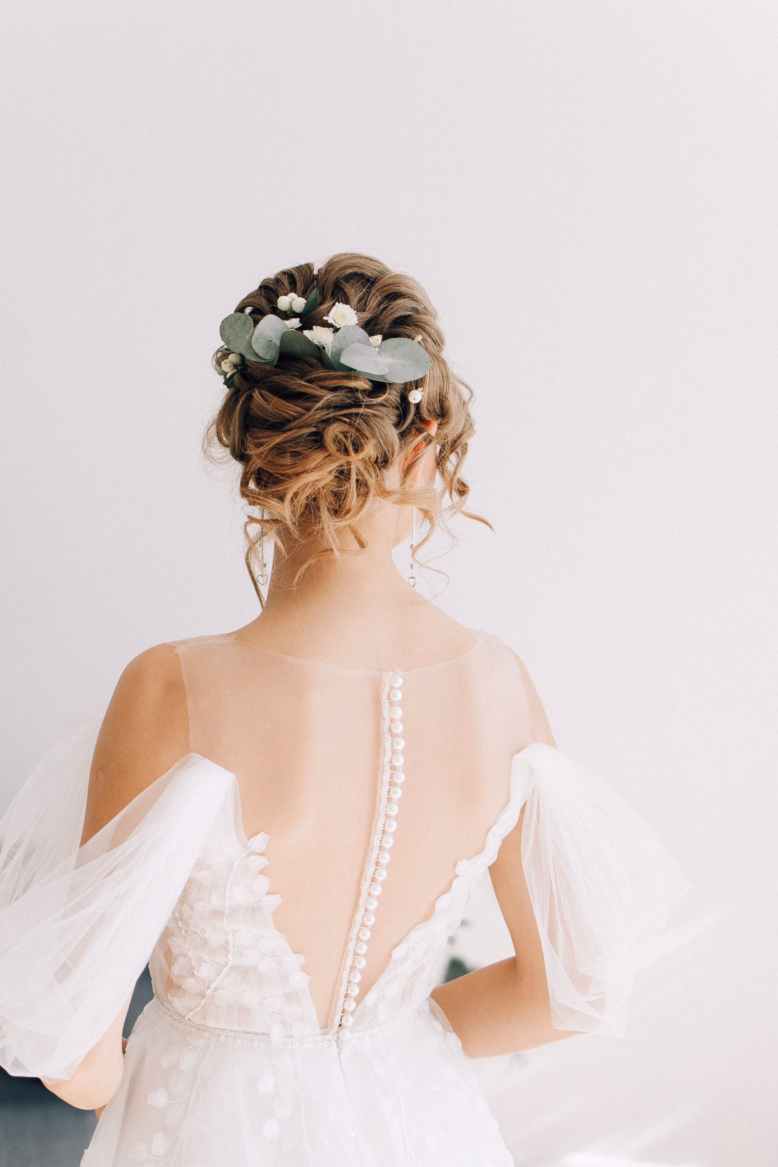 Back view of a bride wearing a curled updo dressed with flowers