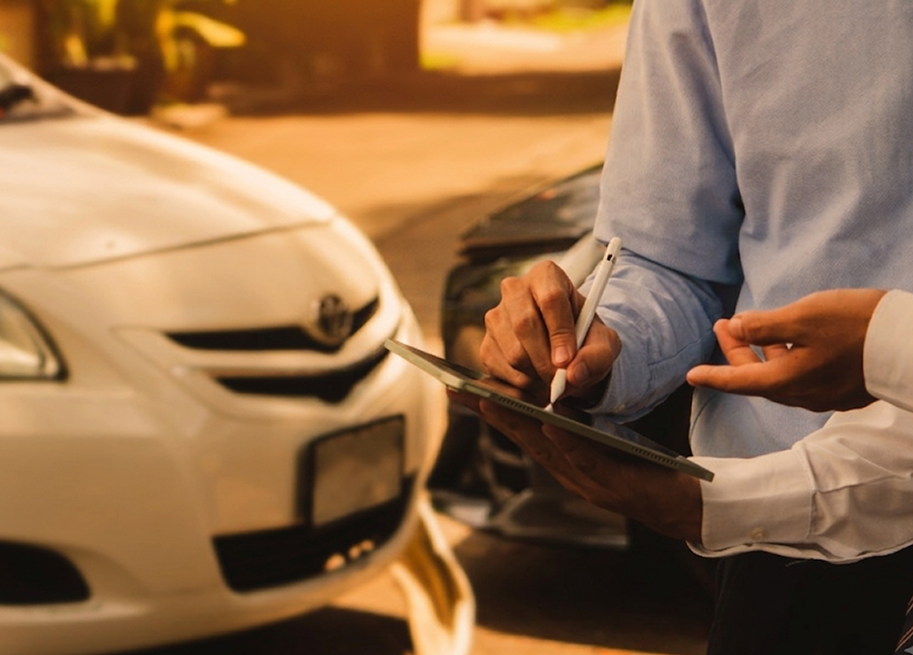 Adjuster recording car damage on a tablet after an accident