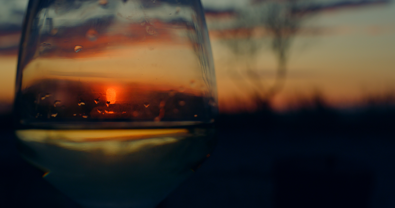 Glass of wine with a sunset reflected in it