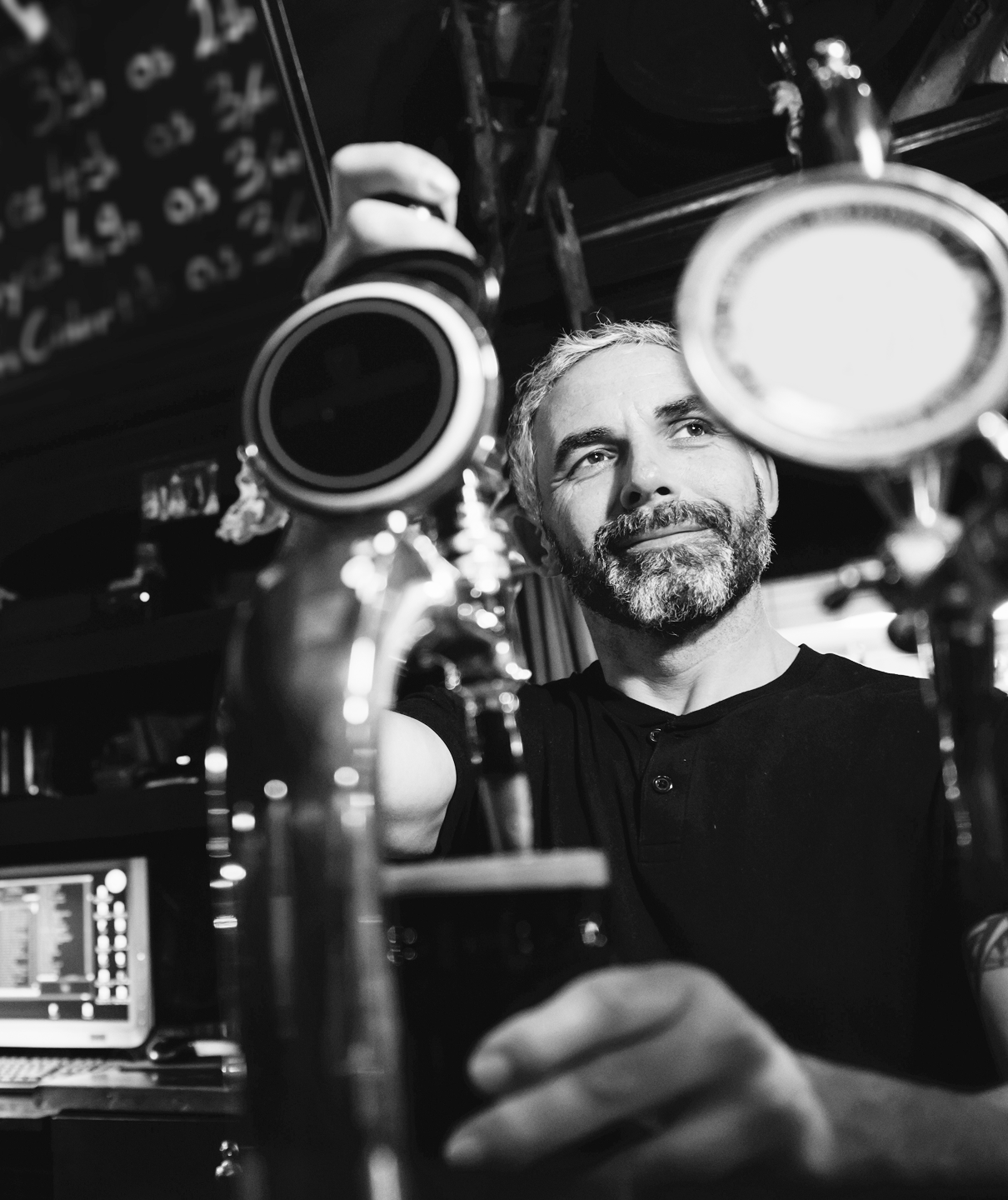 Bartender pulling a pint at a bar tap in black and white