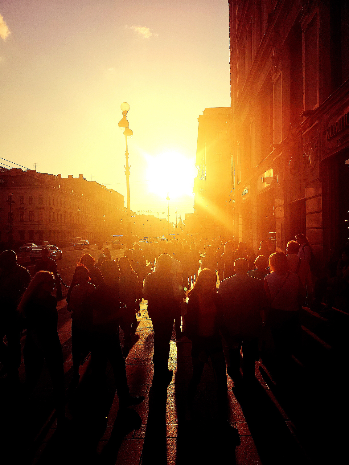 Crowd walking down a city street at sunset