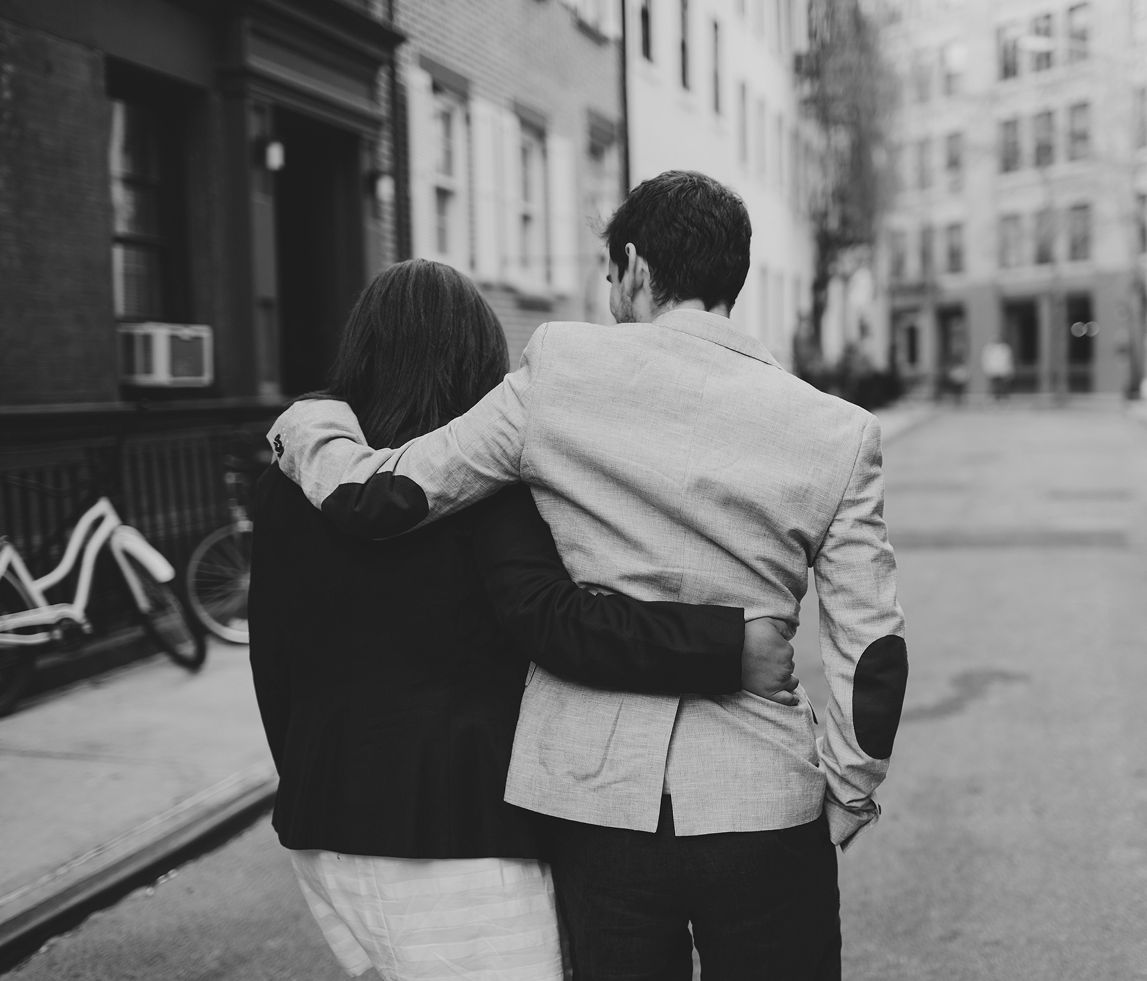 Couple walking arm in arm down a city street in black and white