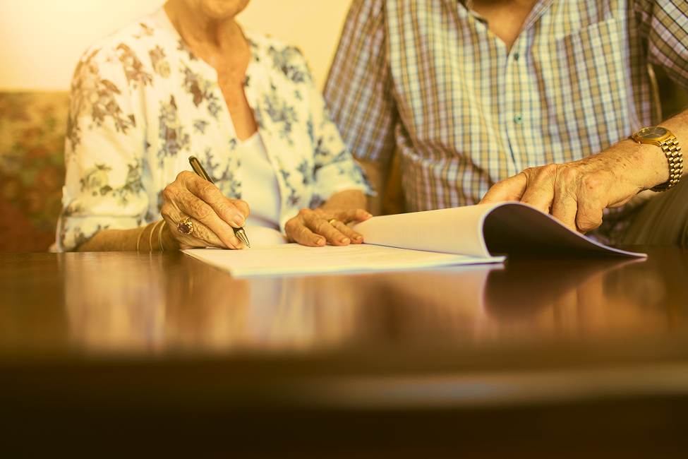 Two people reviewing and signing documents together at a table