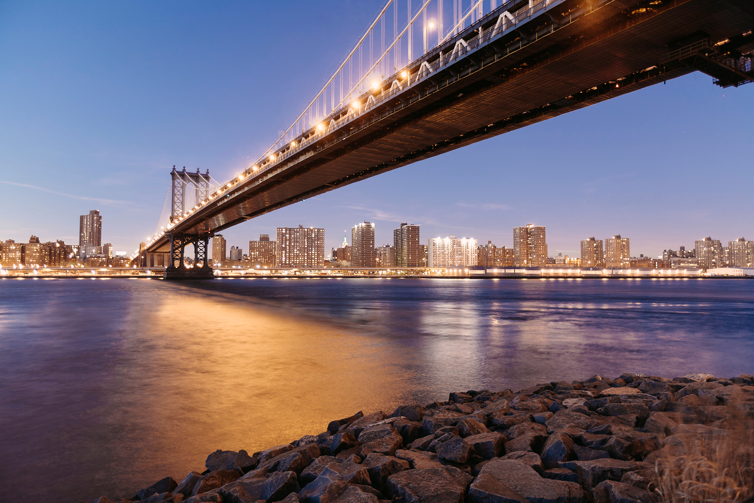 Manhattan Bridge lit up at dusk over the East River