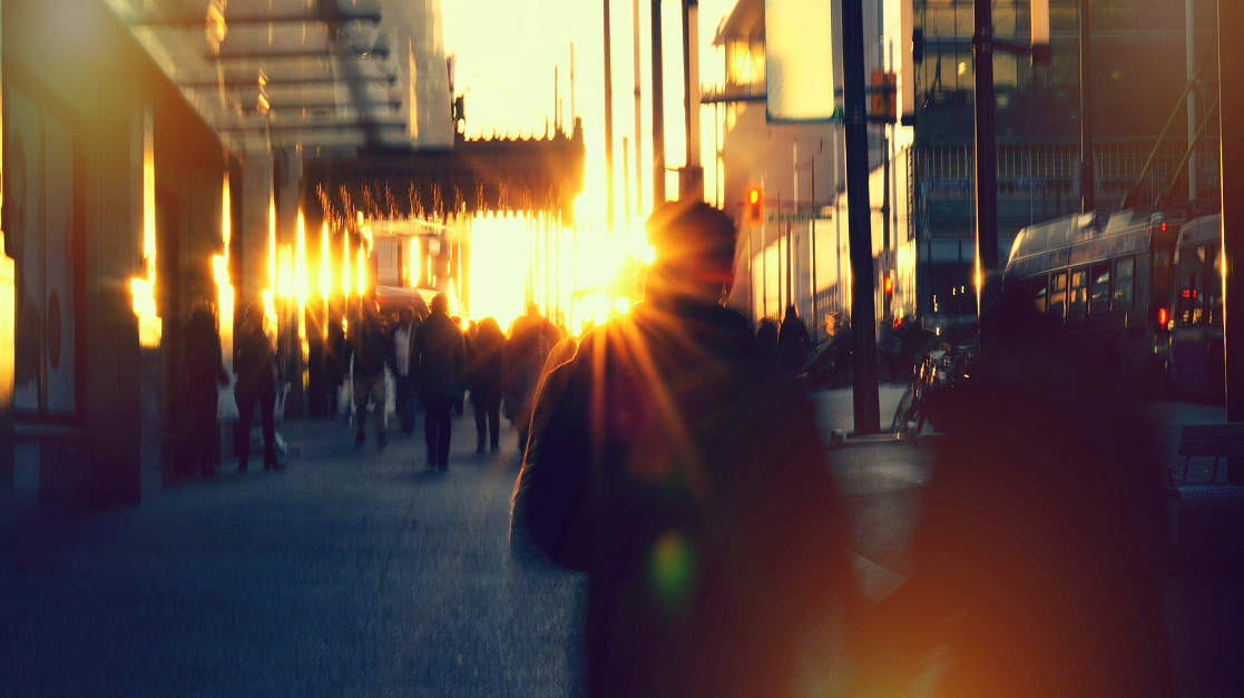Commuters walking through a city street at sunset