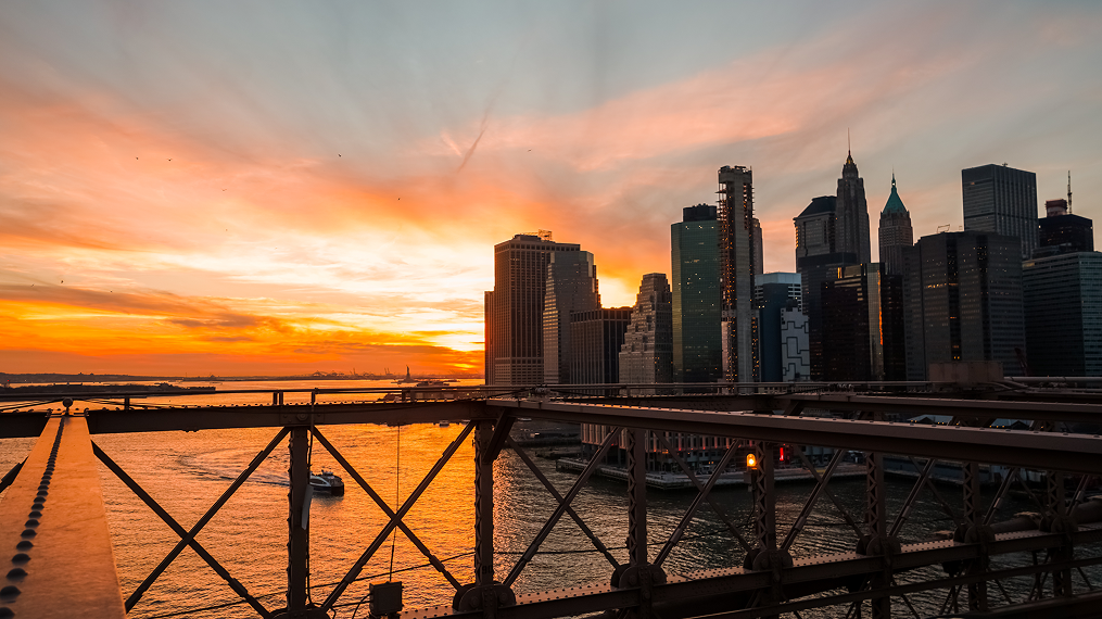 Brooklyn Bridge railing with the Lower Manhattan skyline at sunset
