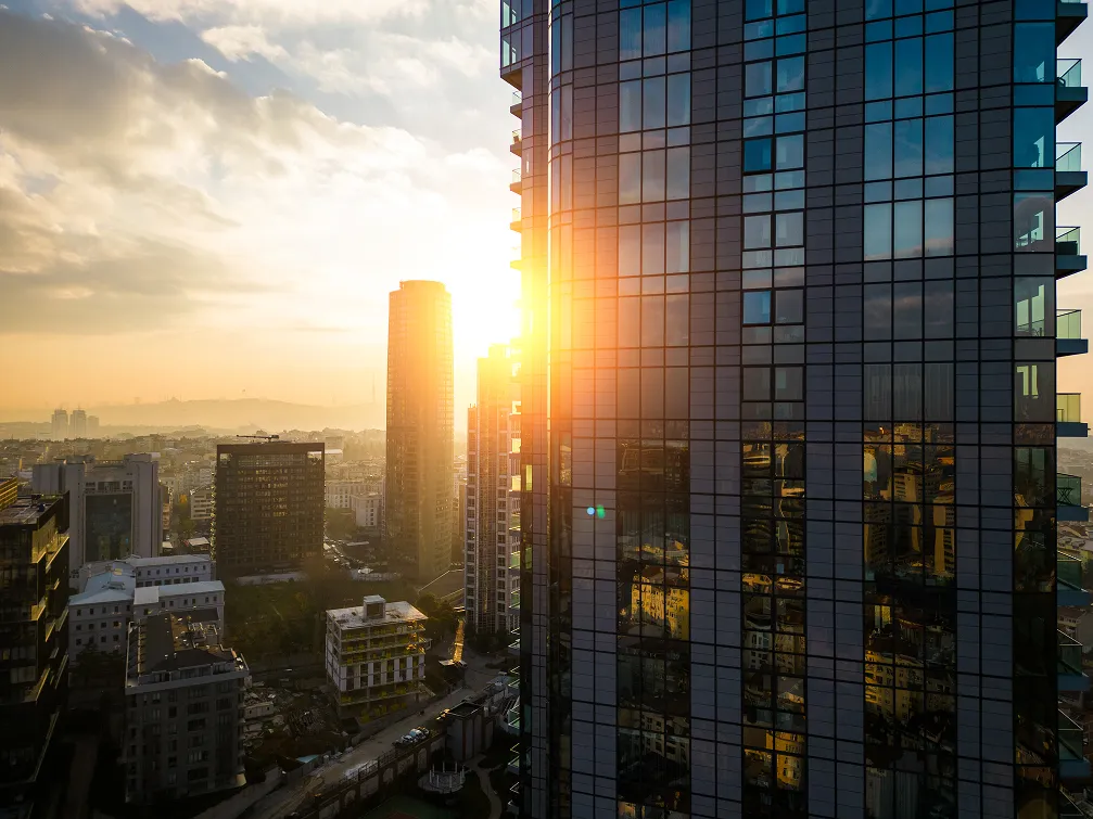 Glass residential tower beside the New York skyline at sunset
