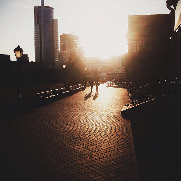 Couple walking across a sunlit plaza at dusk