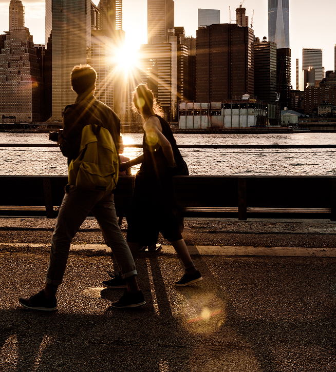 Couple walking along the waterfront with the Manhattan skyline at sunset