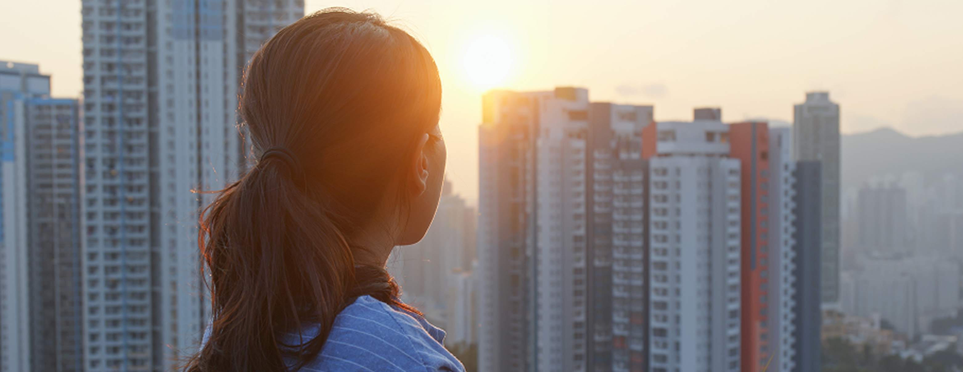 Woman looking out over city high-rises at sunrise