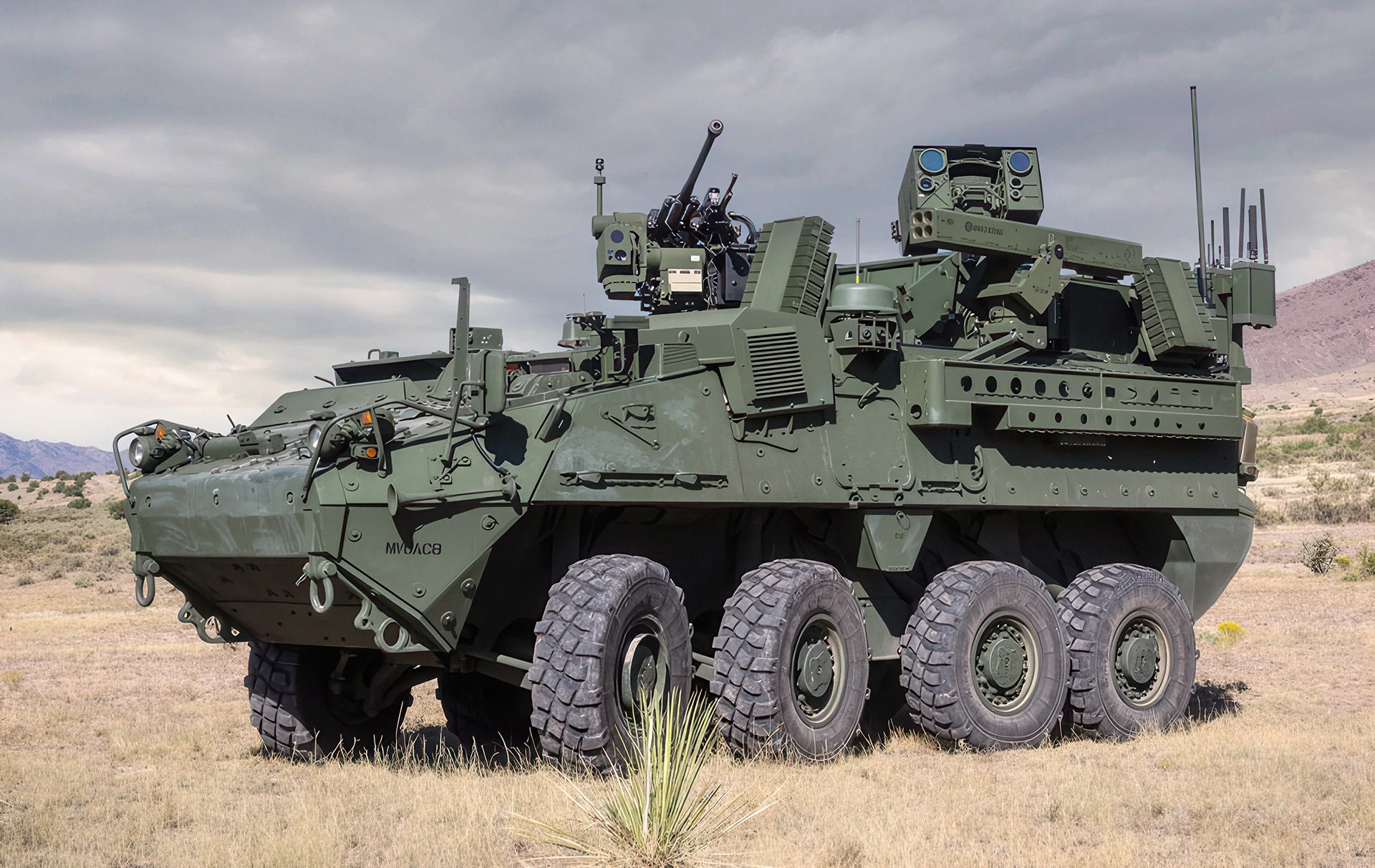Green eight-wheeled vehicle equipped with a mounted EchoGuard radar system, parked on dry grassland under a cloudy sky.