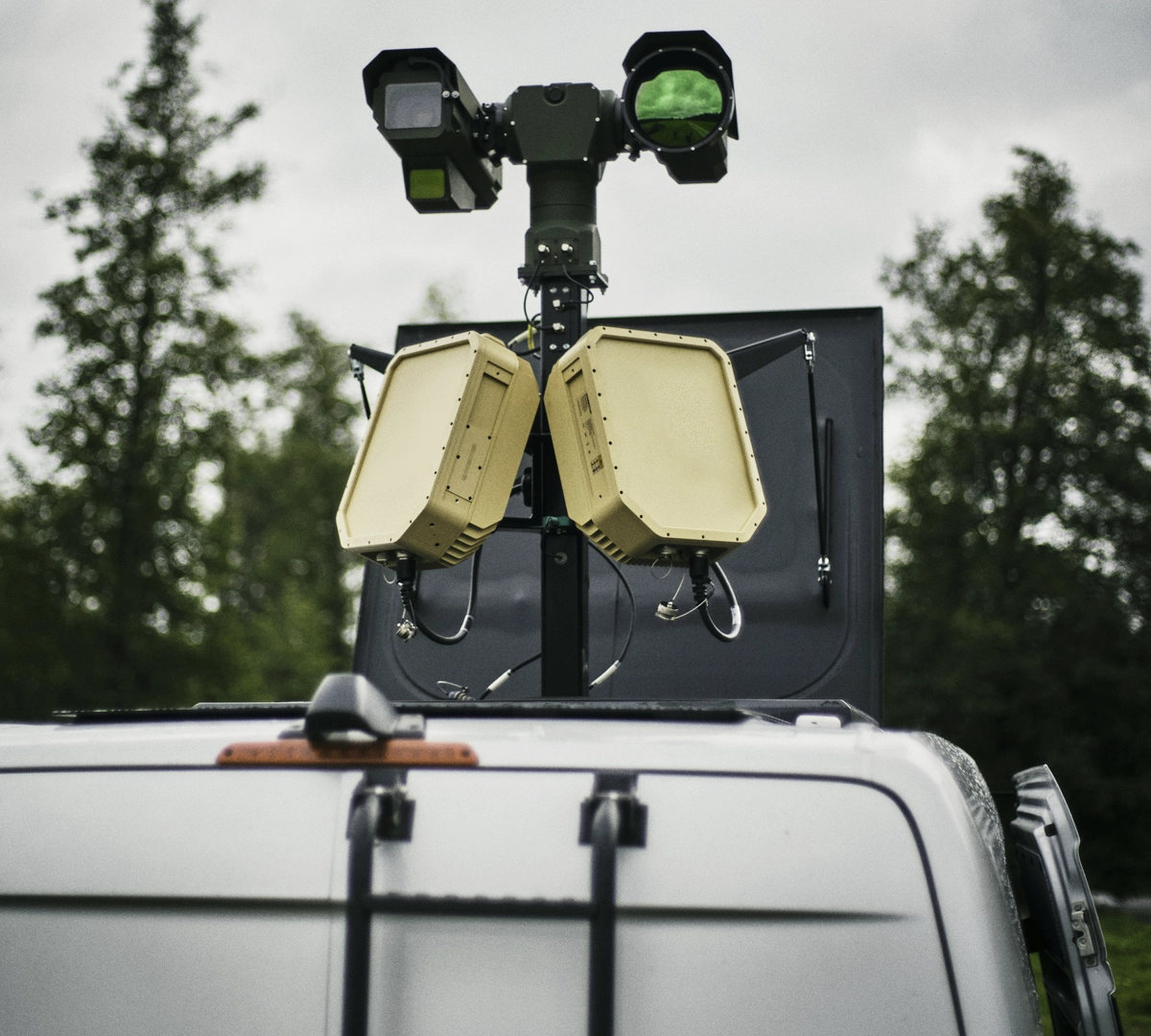 Close-up of EchoShield equipment mounted on the roof of a white vehicle with trees in the background.
