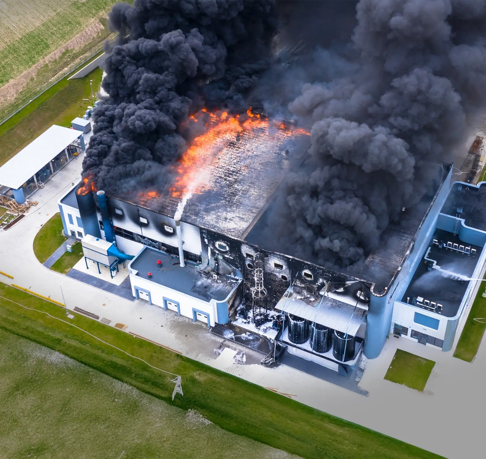 A large building engulfed in flames and thick black smoke during a fire emergency.