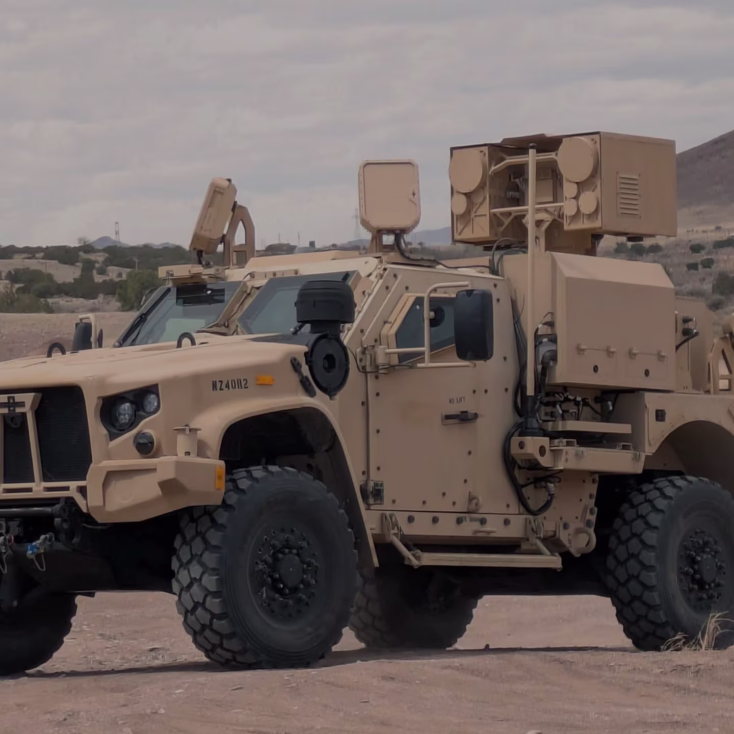Tan military armored vehicle with medium-range radars parked on desert terrain.