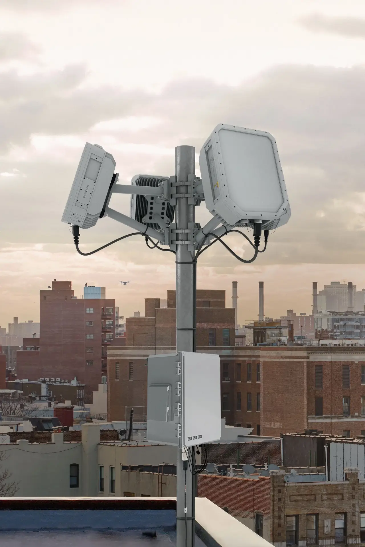 Telecommunication antennas mounted on a rooftop pole with city buildings in the background.