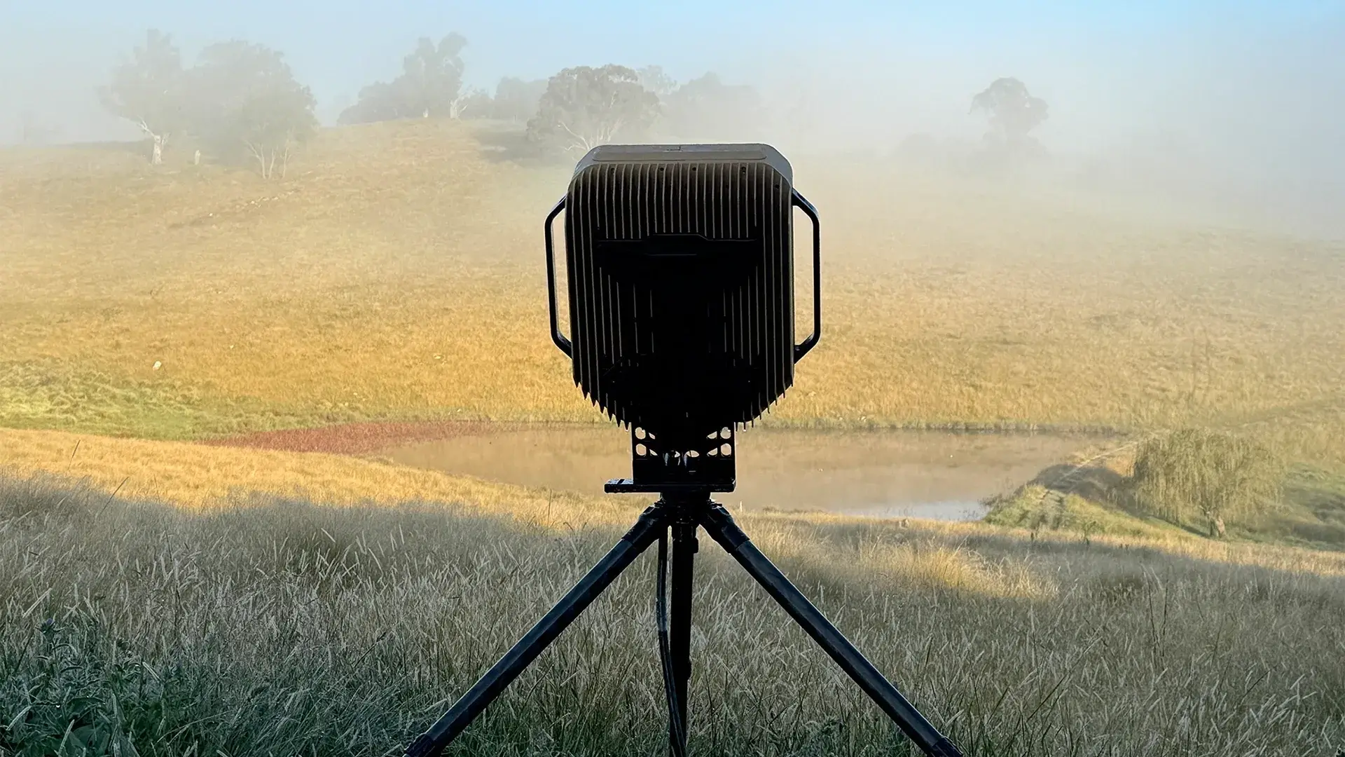 ES Radar on tripod in foggy field with trees and pond in the background.