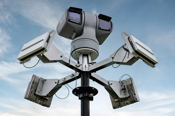 Multi-directional security camera system mounted on a pole against a cloudy sky.