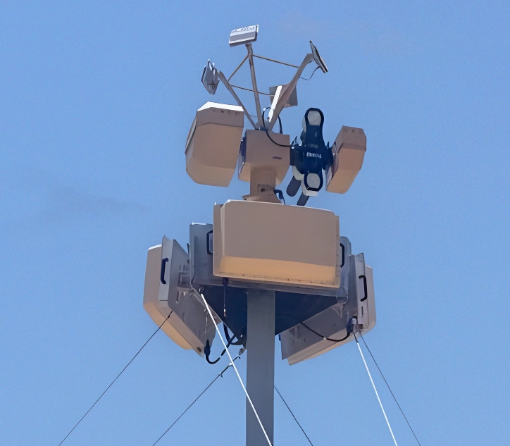 Close-up of a telecommunications tower with multiple antenna panels under clear blue sky.